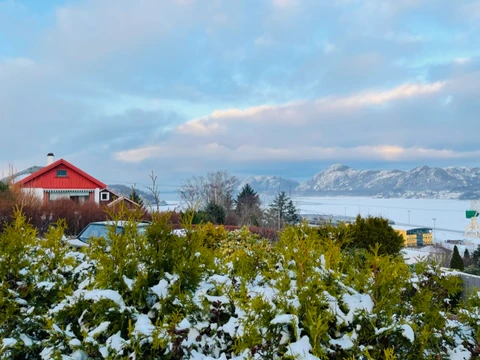 Snowy Norwegian village with red cabin and fjord view